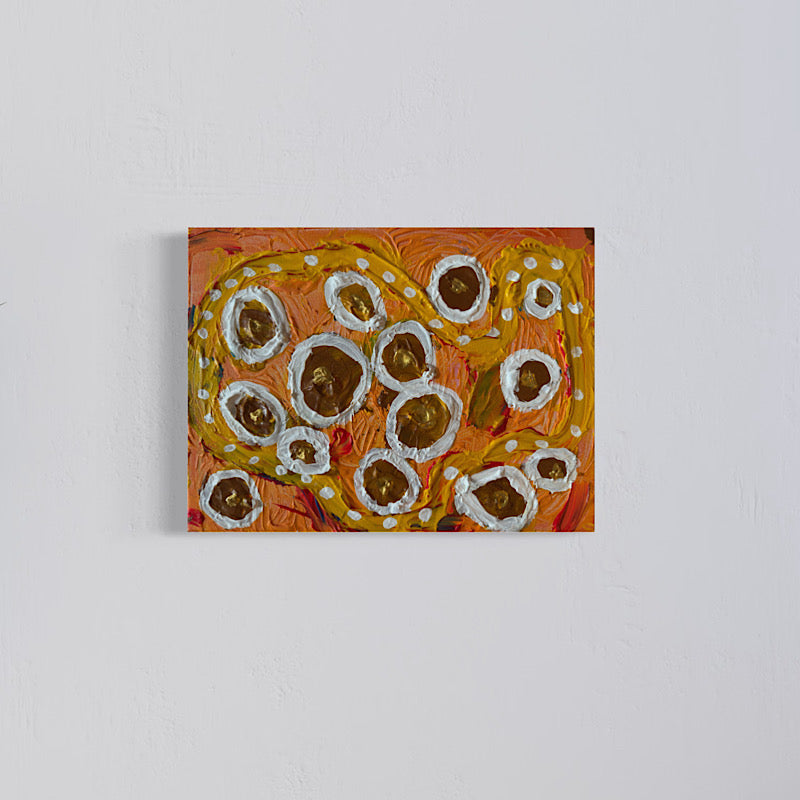 Clara Woods laughing and holding Little Saturn original painting in her studio, vibrant orange and gold canvas with white impasto rings, 16x12 in, 2026