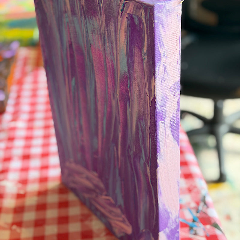 Little Ocean 02, side view of canvas showing deep purple painted edges and thick acrylic texture, displayed on red checkered tablecloth in studio