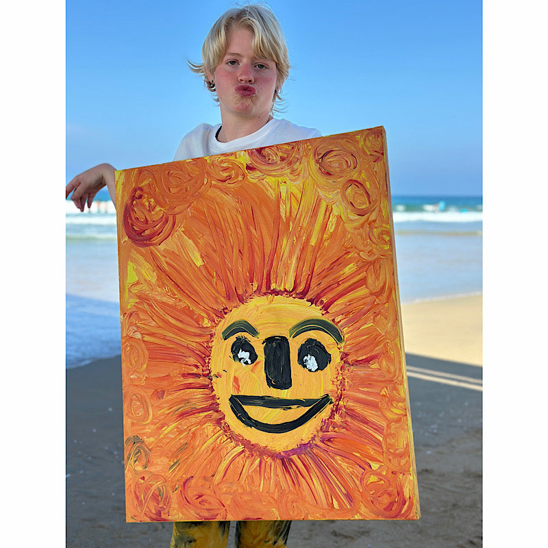 Sunny, Original by Clara Woods — 30x24 in acrylic on canvas, vibrant orange and yellow sun with a smiling face, wall view with neutral vases and open book